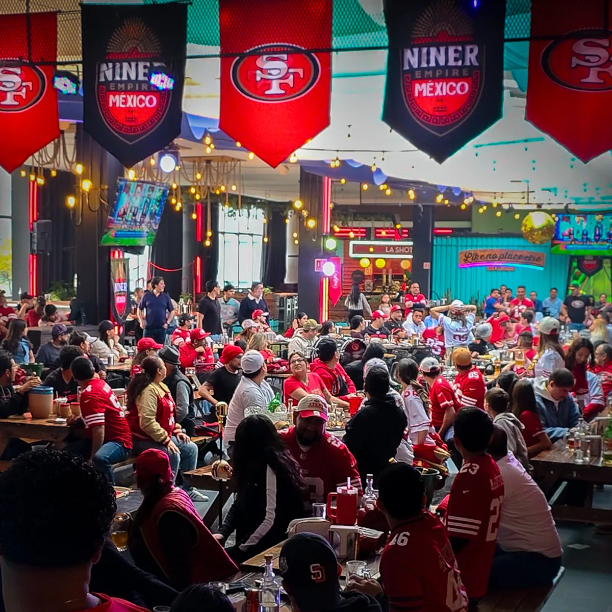 Vista amplia de la sede llena de miembros bajo banderines de los 49ers y Niner Empire México
